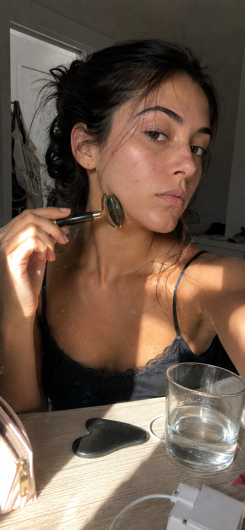 Model using a jade face roller in natural sunlight